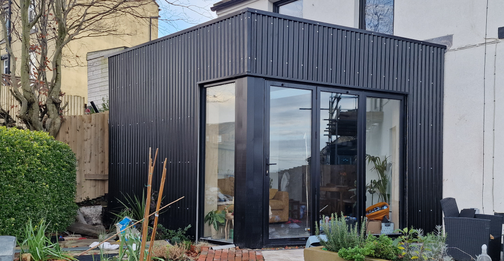 A contemporary black corrugated clad extension with bifolding doors.