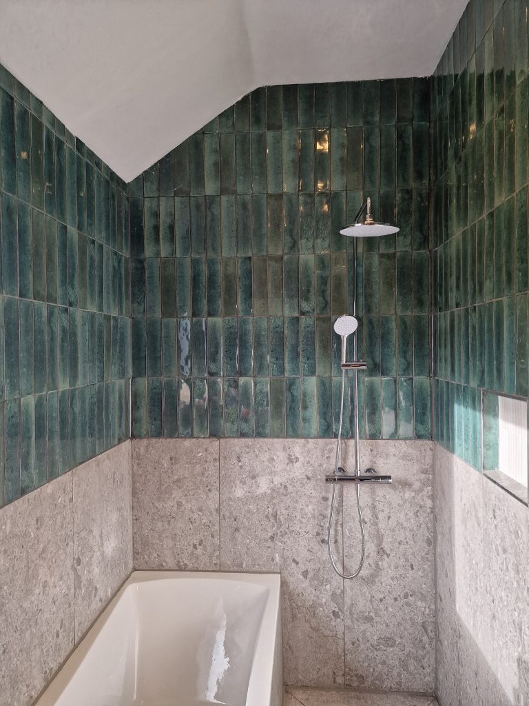 Bathroom with bottle green metro tiles and concrete effect tiles.